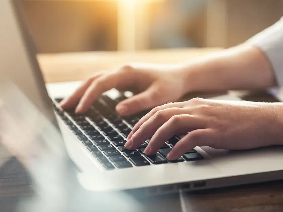 Zwei Hände auf der Tastatur eines Laptops
